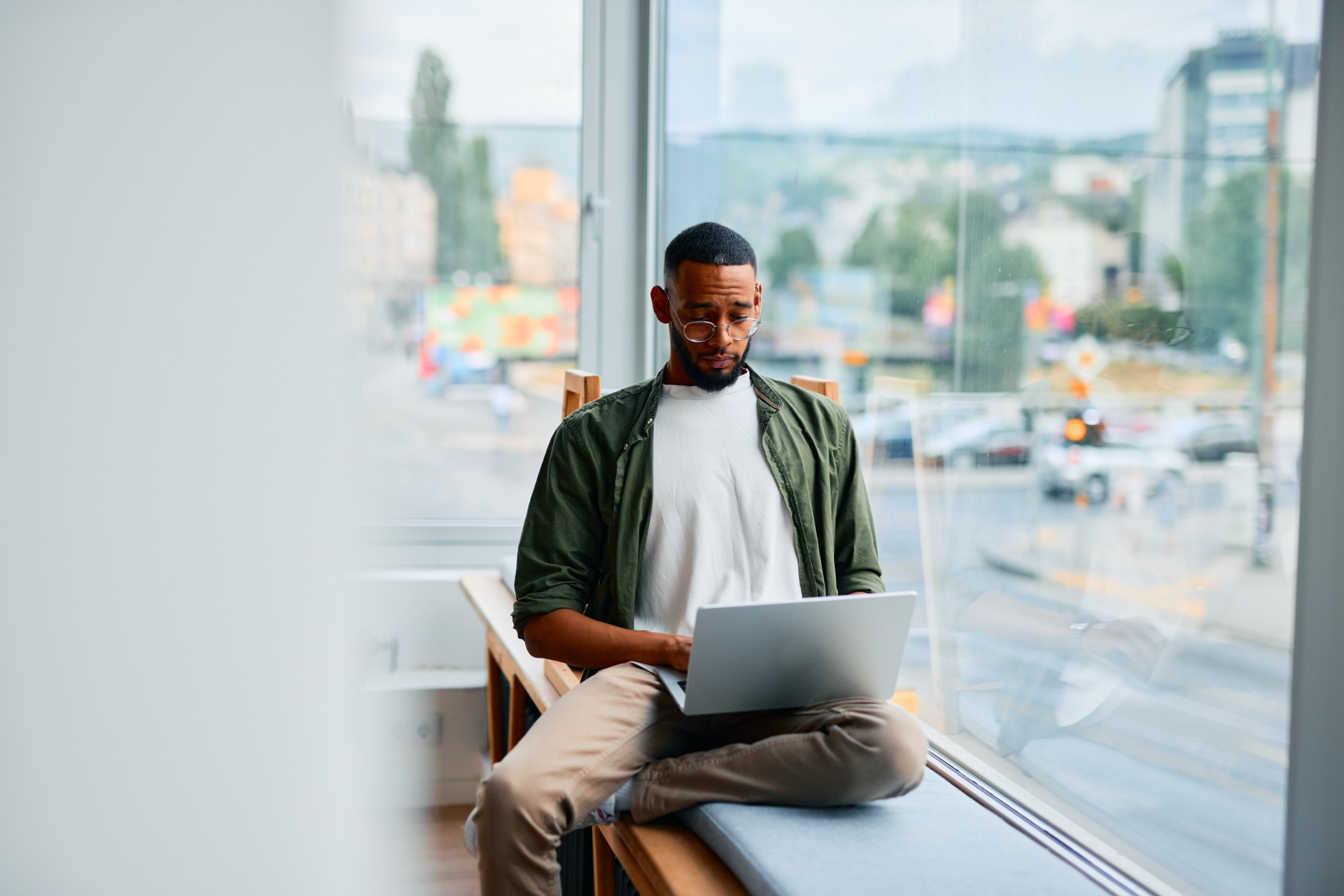 Someone using a laptop by a window overlooking a city street