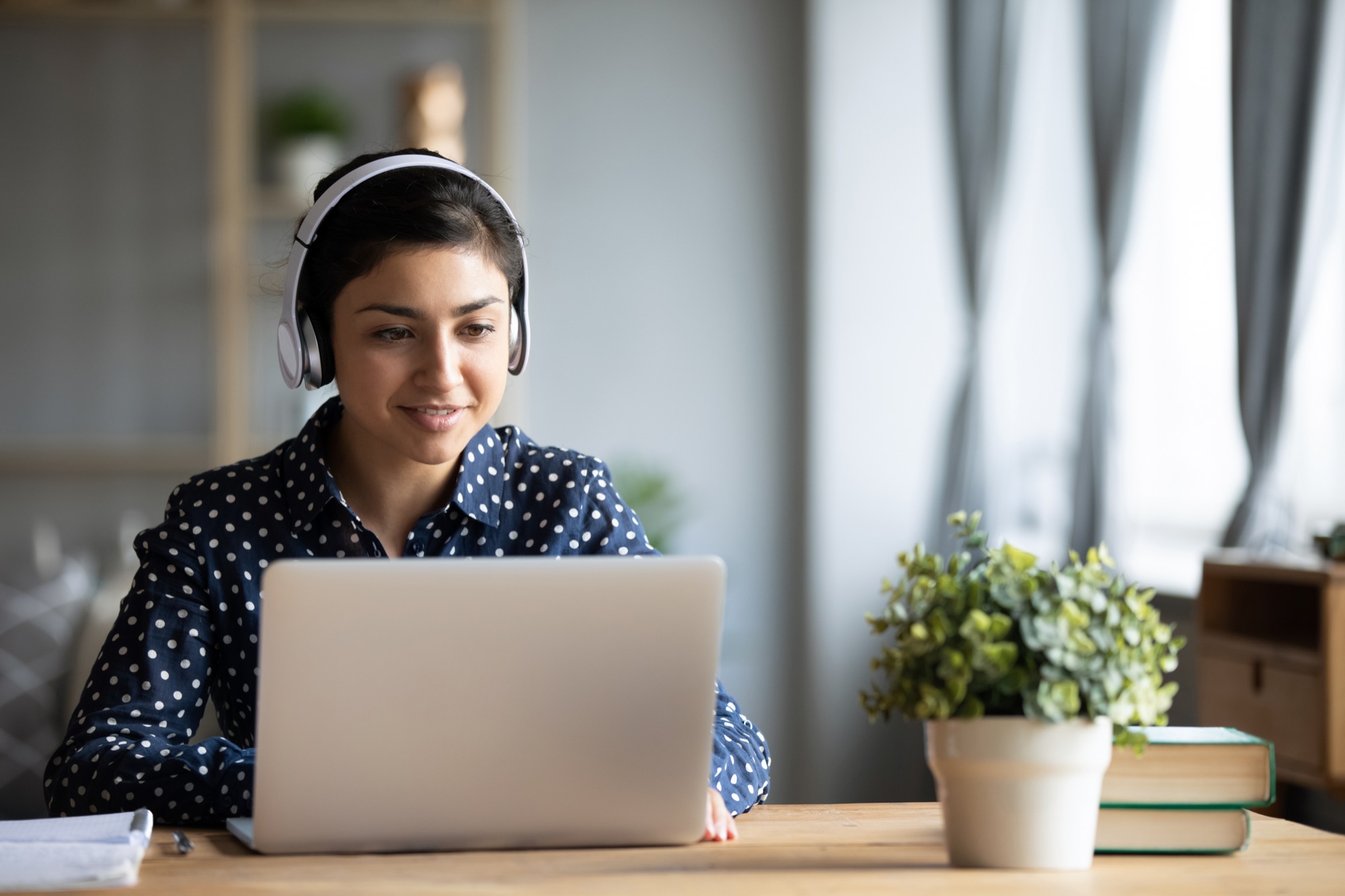 Someone using a laptop with headphones in a home office