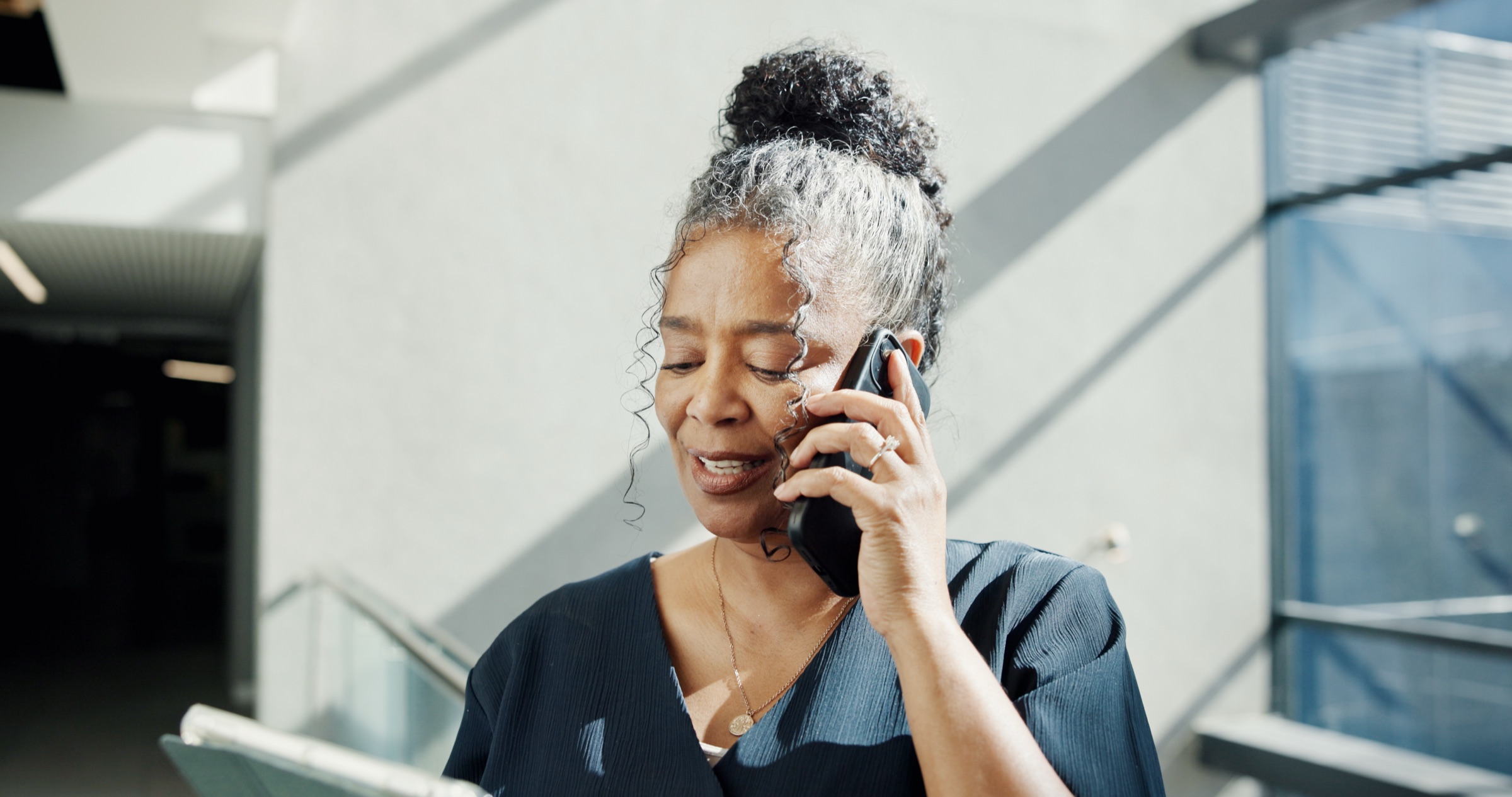 A specialist on the phone while reviewing documents in an office stairwell